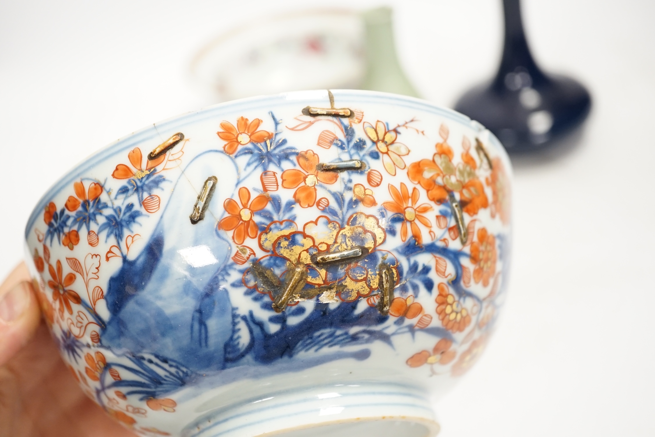 A Chinese famille rose bowl, an Imari patterned bowl, a small blue glazed vase and a similar celadon glazed vase, 18th century and later. Condition - both bowls badly cracked, overall poor